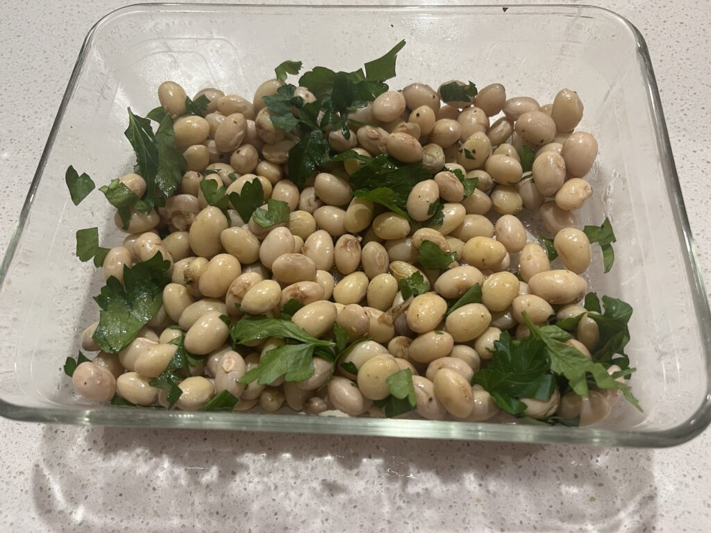 A rectangular glass dish containing beans and parsley.