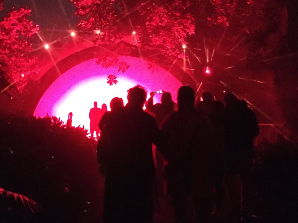 Silhouettes of people walking toward a large semicircle of light
